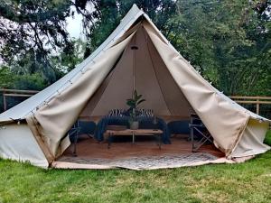a tent with a table and chairs in the grass at Bewley Glamping in Wambrook