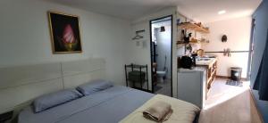 a bedroom with a white bed and a kitchen at Estúdio Glaura in Glaura