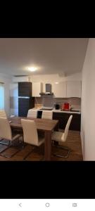 a kitchen with a wooden table and white chairs at Desa's place in Babino Polje