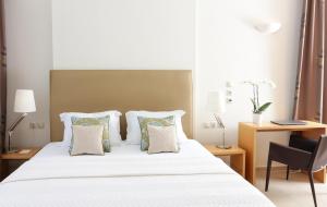 a bedroom with a white bed with pillows and a desk at Chloe Luxury Hotel in Kastoria