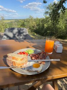 a plate of breakfast food on a table with a glass of orange juice at Söréttorony - A jakuzzis erdei szállás in Kölesd