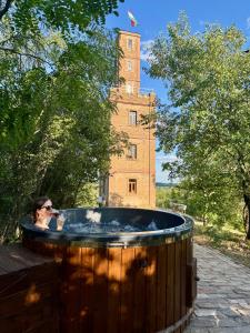 a woman standing in a hot tub in front of a building at Söréttorony - A jakuzzis erdei szállás in Kölesd
