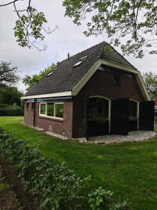 a red brick house with a green yard at Vakantiehuisje 'De Uithof' in Oosterhesselen