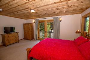 Un dormitorio con una cama roja y un televisor. en Bonanza By Hauserman Rentals, en Tahoe City