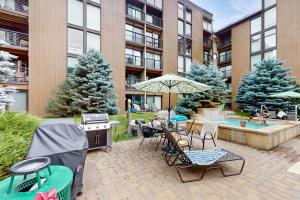 a patio with a grill and chairs and a table with an umbrella at Vail International #3 in Vail
