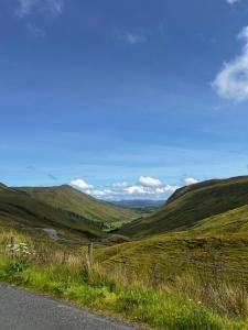 a road through a green hills with a blue sky at Rose Cottage in Killybegs