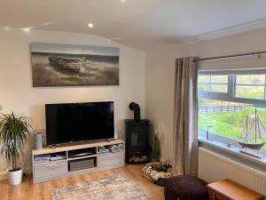 a living room with a flat screen tv and a window at Rose Cottage in Killybegs