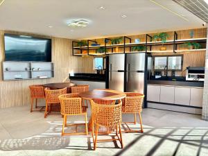 una cucina con tavoli, sedie e frigorifero di DVA Cabedelo Beira-Mar – O Paraíso na Ponta de Cabedelo a Cabedelo