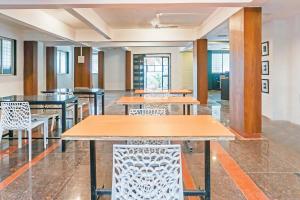 a cafeteria with tables and chairs and windows at OYO 77138 Shree Apartments in Khadki +72 photos