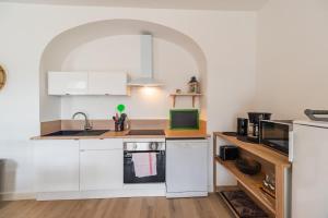 a kitchen with white cabinets and a sink and a microwave at Appartement avec veranda et 3 chambres Guingamp in Guingamp