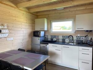 une cuisine avec des armoires blanches, une table et une fenêtre dans l'établissement Holiday Home in Mielenko near Seaside Beach, à Mielenko