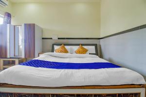 Un dormitorio con una gran cama blanca con almohadas naranjas. en SPOT ON Indirasagar Executive, en Kolhapur