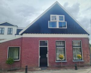 een rood bakstenen huis met een zwart dak bij Tussen poort en toren in Sneek