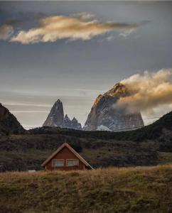 a house in a field with a mountain in the background at La Joaquina, Casa de montaña. in El Chalten