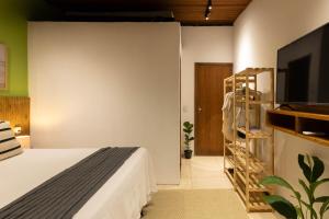 a bedroom with a bed and a flat screen tv at Pituba Ville - Ap Floresta in Itacaré