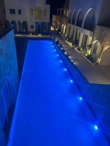 a swimming pool lit up at night with blue lights at Drymades Ruci Rooms in Dhërmi +23 photos