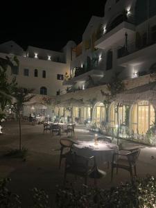 a building with tables and chairs in a courtyard at night at Drymades Ruci Rooms in Dhërmi