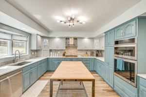 a kitchen with blue cabinets and a wooden table at Private Indoor Hot Tub Fish and Boat on Sylvan Lake in Rome City