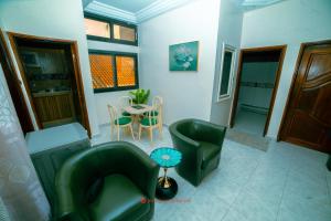 Cabral residence في Guediawaye: غرفة معيشة مع كرسيين أخضر وطاولة