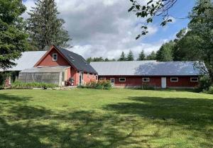 a red barn with a large green field in front of it at Honeypot Farmhouse - Lux Family Retreat at Okemo - Bromley in Weston