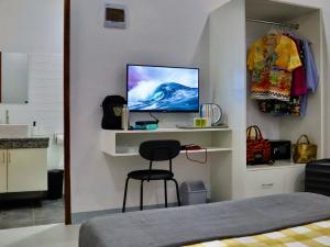 a bedroom with a bed and a chair and a tv at Abitha Prime Rooms in Bantay