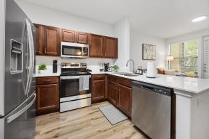 a kitchen with stainless steel appliances and wooden cabinets at Brightshaven CoolSprings, Modern 1Bed with EV Parking in Frisco in Frisco +4 photos