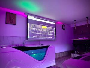a purple room with a tub with a large screen at L'escale du Donon - Chambre Blanche in Grandfontaine