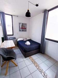 a bedroom with a bed and a chair in it at Pequeña habitación London en GDL in Guadalajara