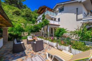 een patio met stoelen en tafels en een gebouw bij Apartments Mirjana T. in Supetarska Draga