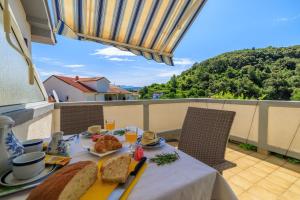 een tafel met eten en brood op een balkon bij Apartments Mirjana T. in Supetarska Draga