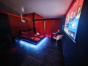 a room with a bed with red curtains and a television at L'Escale du Donon - Chambre Noire in Grandfontaine
