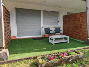 a patio with two chairs and a table and some flowers at L'Escale du Donon - Chambre Noire in Grandfontaine