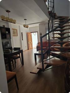 a living room with a spiral staircase and a table at Céntrico adosado cerca de la playa in Punta Umbría