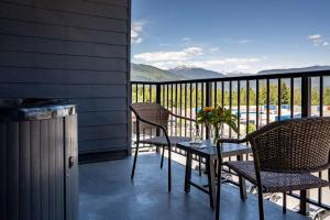 einen Balkon mit 2 Stühlen und einem Tisch mit Blumen darauf in der Unterkunft Revytalise - Cozy 3 Bedroom Condo in Revelstoke