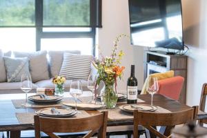 einen Esstisch mit einer Flasche Wein und Gläsern in der Unterkunft Revytalise - Cozy 3 Bedroom Condo in Revelstoke