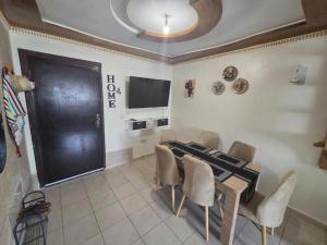 a dining room with a black door and a table and chairs at CHU Mohammed VI Appartement in Daidatz
