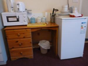a kitchen with a desk with a microwave and a refrigerator at Aberdeen Arms Hotel Tarland in Tarland
