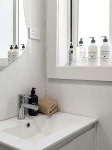 a white bathroom with a sink and a mirror at The Fletcher Bondi in Sydney