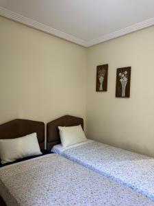 two beds sitting next to each other in a bedroom at trqnche 5 imm k rsd no 189 riad essalam in Tangier