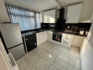 a kitchen with white cabinets and a washer and dryer at 3 bedroom Luxurious Property in Manchester