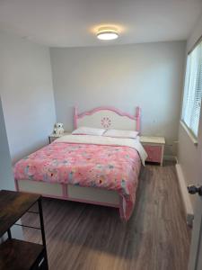 a bedroom with a pink bed and a wooden floor at Maplewood Hostel in Vancouver