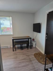 a living room with a table and a tv at Maplewood Hostel in Vancouver