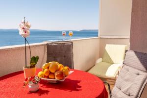 einen Tisch mit einer Schale Obst und zwei Gläsern Wein in der Unterkunft Apartments Sinovcic with terrace & sea view, 4 min walk to the beach in Podstrana