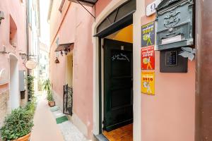a narrow alleyway with a green door in a pink building at Romantic room nel Borgo di Cervo in Cervo