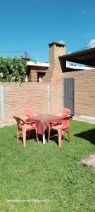 three red tables and benches sitting on the grass at Dpto Marina in Villa Cura Brochero +1 photo