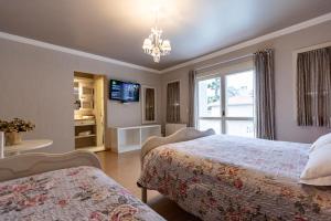a bedroom with two beds and a television and a window at Doce Canela - Pousada de Charme in Canela