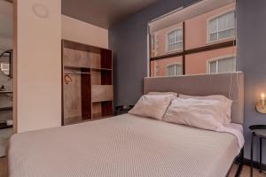 a bedroom with a white bed with a window at Soy Local Parque La 93 in Bogotá