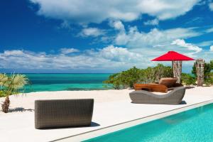 a pool with chairs and an umbrella on the beach at Beachfront luxury 2 bedroom villa on Grace Bay in Providenciales