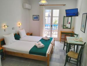 ナクソス・コラにあるNostos Studios at Saint George beach Agios Georgios Chora Naxos townのベッドとテーブルとテレビのある寝室