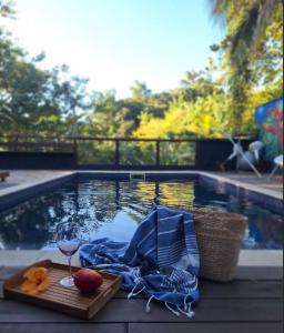 a table with a glass of wine next to a swimming pool at Encantos da Ilha mais Bela - 150m das praias Viana e Siriúba in Ilhabela